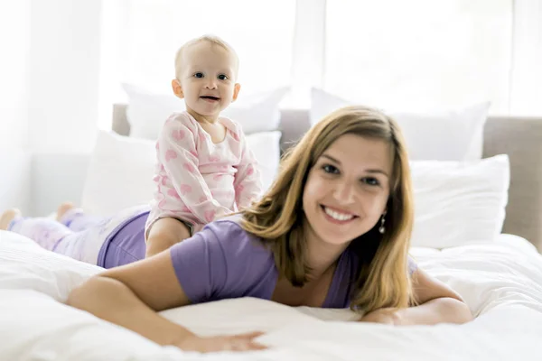 Madre feliz con el bebé acostado en la cama en casa — Foto de Stock