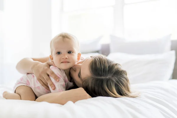 Счастливая мать с ребенком, лежащим на кровати дома — стоковое фото