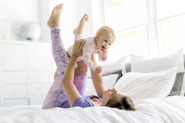 Happy mother with baby lying on bed at home — Stock Photo, Image