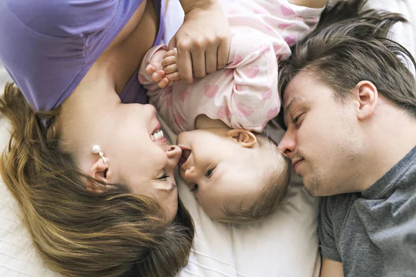 Portrait of beautiful young parents and cute baby on bed — Stock Photo, Image