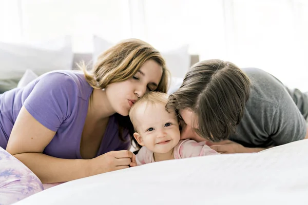 Портрет красивых молодых родителей и милый ребенок на кровати — стоковое фото