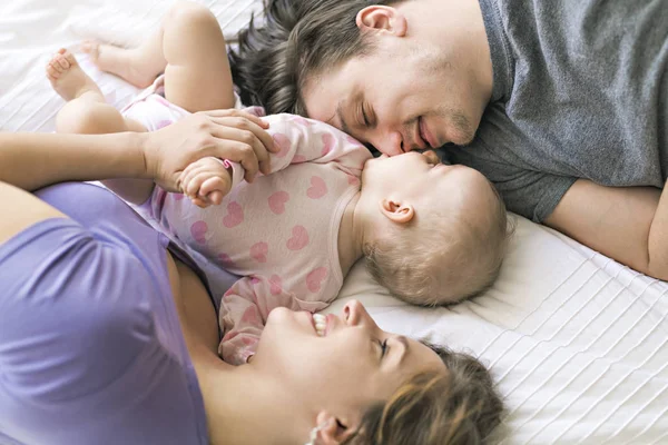 Retrato de belos pais jovens e bebê bonito na cama — Fotografia de Stock