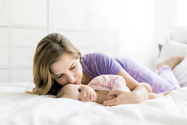 Madre feliz con el bebé acostado en la cama en casa — Foto de Stock