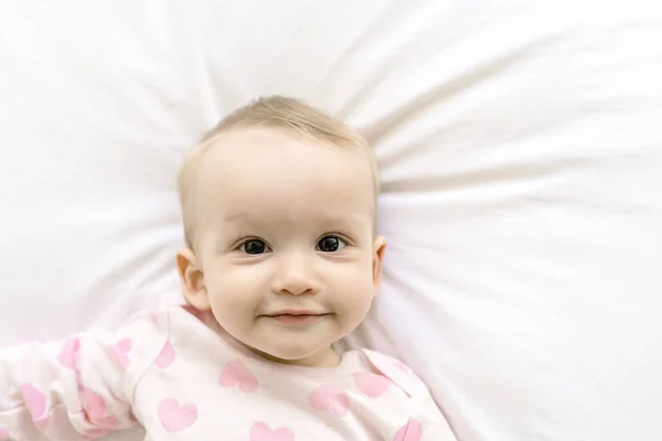Entzückende Babydecke mit weißem Laken in rosa Kleidung — Stockfoto