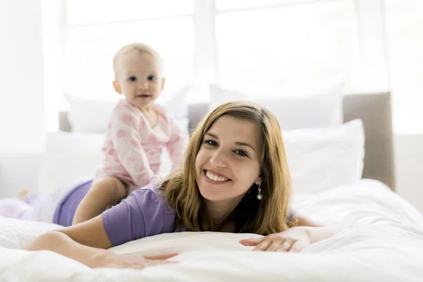 Happy mother with baby lying on bed at home Stock Photo