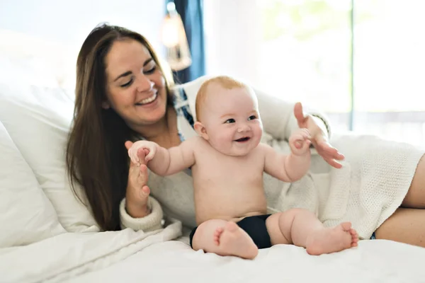 Mãe feliz com bebê na cama em casa — Fotografia de Stock