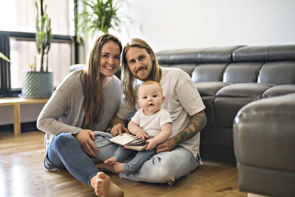 Famille avec son bébé et un livre dans le salon — Photo