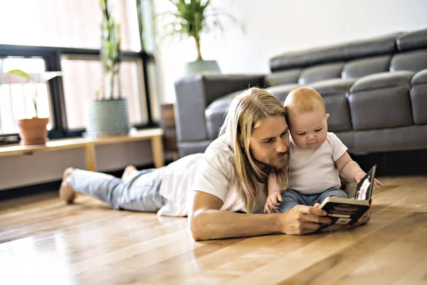 Apja a baba, és egy könyvet a nappaliban — Stock Fotó