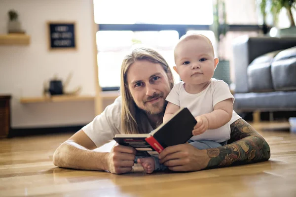 Padre con su bebé y un libro en la sala de estar —  Fotos de Stock