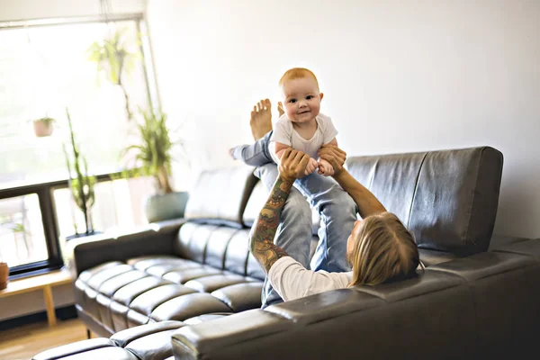 父の自宅のソファの上の赤ちゃんの娘と遊ぶ — ストック写真