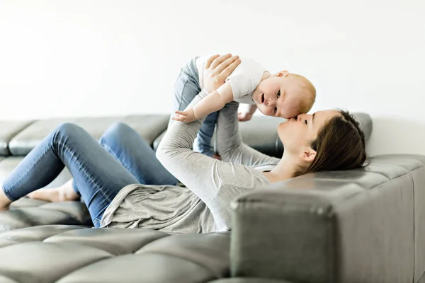 Madre con hija bebé en el sofá en casa — Foto de Stock