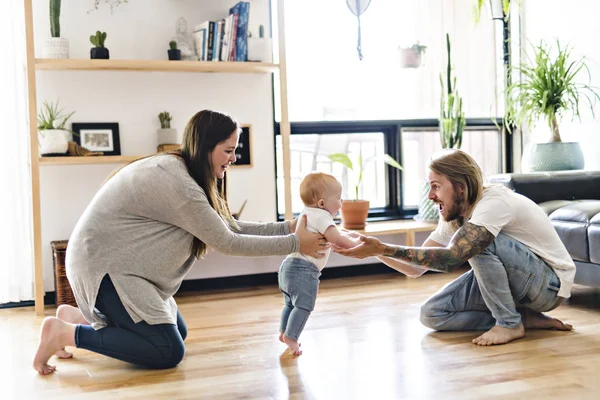 Överordnade hjälp Baby dotter ta första stegen hemma — Stockfoto