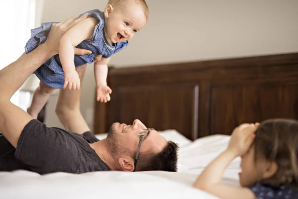 Vader speelt met haar baby in de slaapkamer — Stockfoto