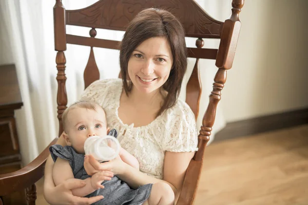 Mother holding and feed her baby child on chair — Stock Photo, Image