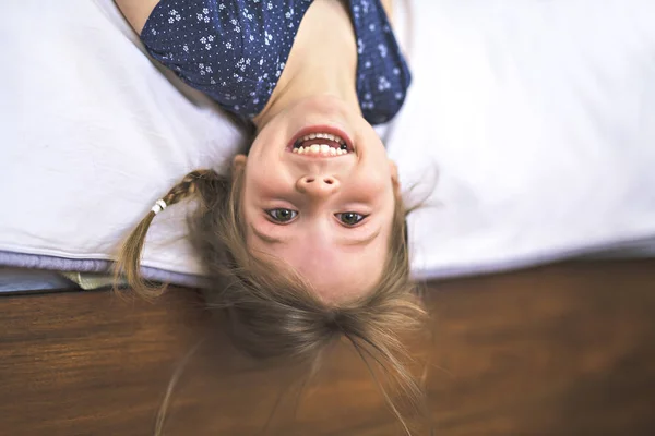 Маленькая красивая девочка в спальне вверх ногами — стоковое фото