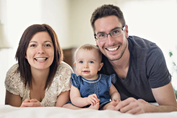 Lyckliga familjen mamma, Pappa och baby hemma i sängen — Stockfoto