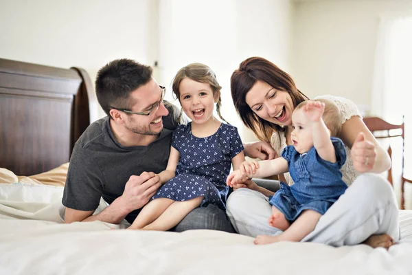 Šťastné rodiny matku, otce a dvě děti doma v posteli — Stock fotografie