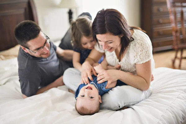 Gelukkige familie moeder, vader en twee kinderen thuis in bed — Stockfoto