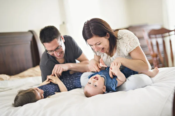 Família feliz mãe, pai e dois filhos em casa na cama — Fotografia de Stock