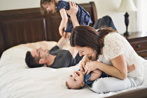 Gelukkige familie moeder, vader en twee kinderen thuis in bed — Stockfoto