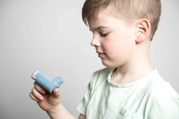 Menino usando sua bomba de asma no estúdio fundo branco — Fotografia de Stock
