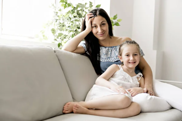 美しい母とソファに一緒に座って彼女の小さな娘の肖像画 — ストック写真