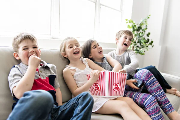 Kindergruppe isst gemeinsam Popcorn auf Sofa — Stockfoto