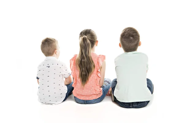 Visão traseira do grupo infantil sentado no chão olhando para a parede — Fotografia de Stock