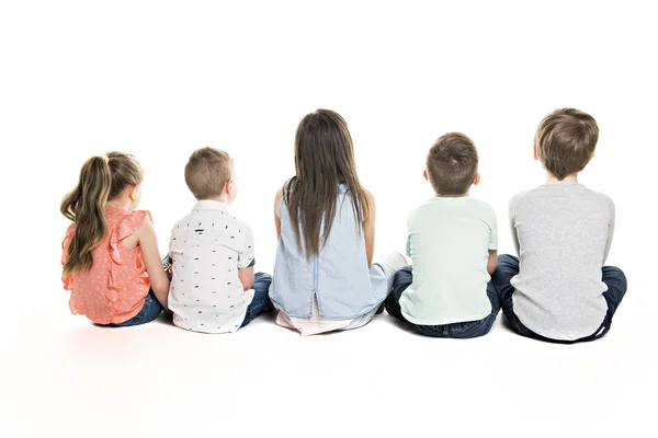 Visão traseira do grupo infantil sentado no chão olhando para a parede — Fotografia de Stock