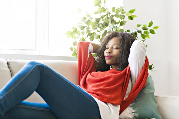 Çekici siyah genç kadın evde kanepede rahatlatıcı — Stok fotoğraf
