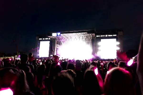 Parlak sahne ışıkları önünde konser kalabalığının siluetleri. — Stok fotoğraf