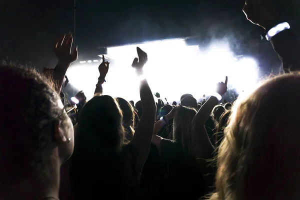 Silhuetas de multidão de concerto na frente de luzes de palco brilhantes. — Fotografia de Stock