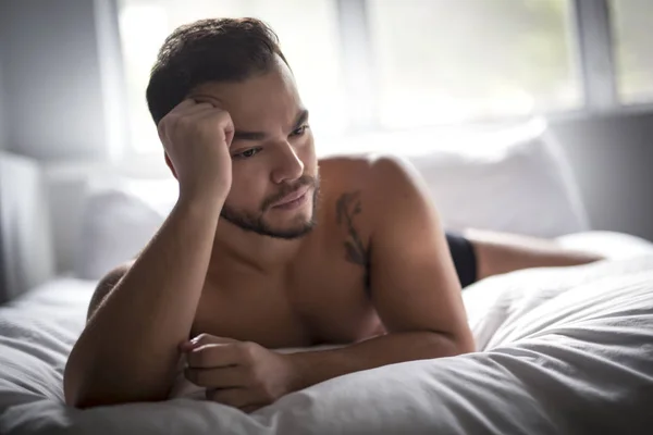 Ein junger mexikanischer Mann ohne Hemd im weißen Bett — Stockfoto