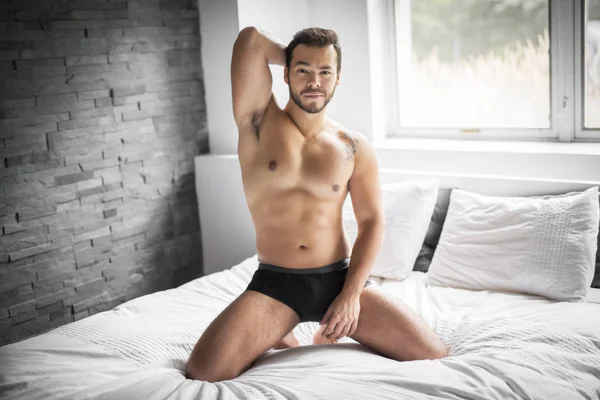 A young mexican man shirtless in white bed