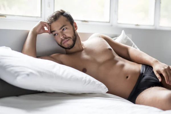 Młody człowiek z Meksyku, shirtless w białe łóżko — Zdjęcie stockowe