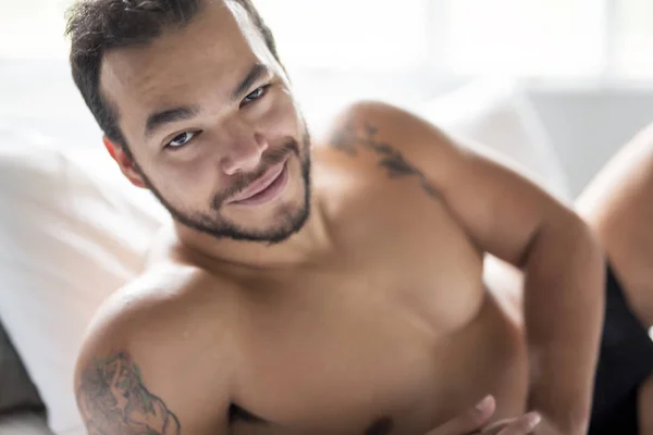 A young mexican man shirtless in white bed — Stock Photo, Image