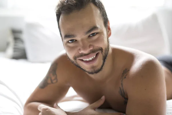 Ένας νεαρός άνδρας Μεξικού shirtless λευκό κρεβάτι — Φωτογραφία Αρχείου