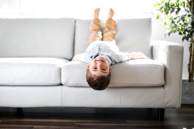 Young Boy Relaxing On Sofa At Home clipart