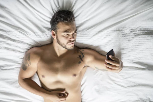 Un joven mexicano sin camisa en una cama blanca —  Fotos de Stock