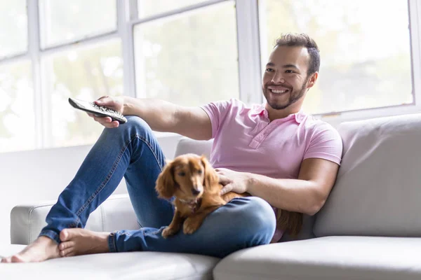 Ein netter mexikanischer Mann auf dem Sofa mit Hund — Stockfoto