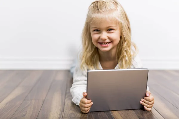 Child with tablet lying on floor. Girl playing laptop computer — Stock Photo, Image