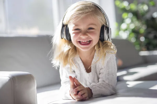 ソファのリビング ルームで横になっている幸せな小さな女の子リスニング音楽 — ストック写真