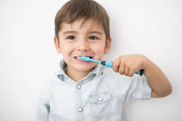 Smiley chłopiec czyści zęby na białym tle na szarym tle — Zdjęcie stockowe