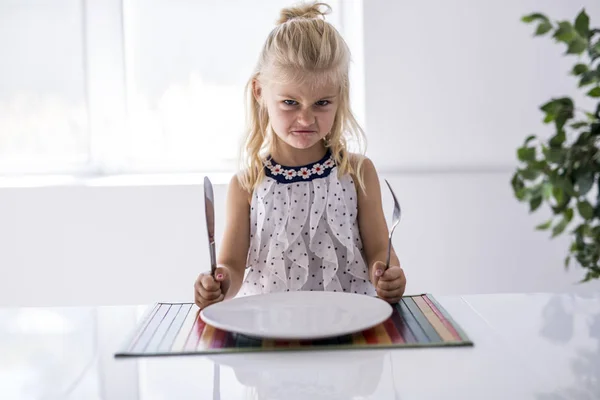 Woedend meisje te wachten voor het diner. Een vork houden in de hand — Stockfoto