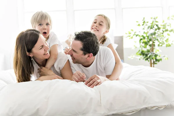 Familie van vier plezier op het bed thuis — Stockfoto