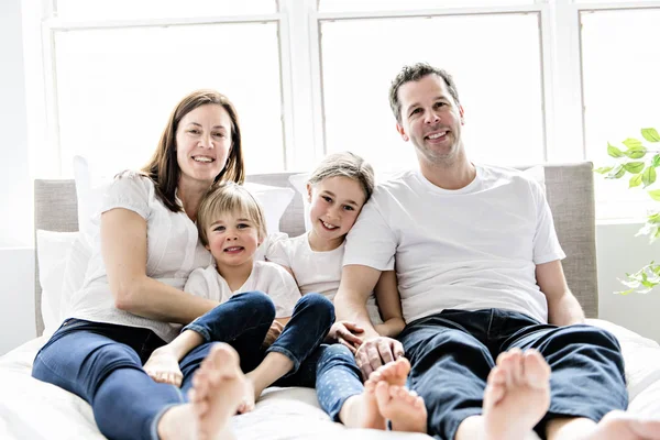 Familie van vier plezier op het bed thuis — Stockfoto