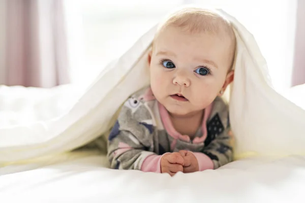 En söt flicka på en vit säng hemma — Stockfoto