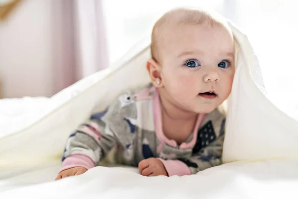 Une jolie petite fille sur un lit blanc à la maison — Photo