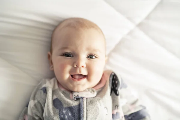 Une jolie petite fille sur un lit blanc à la maison — Photo