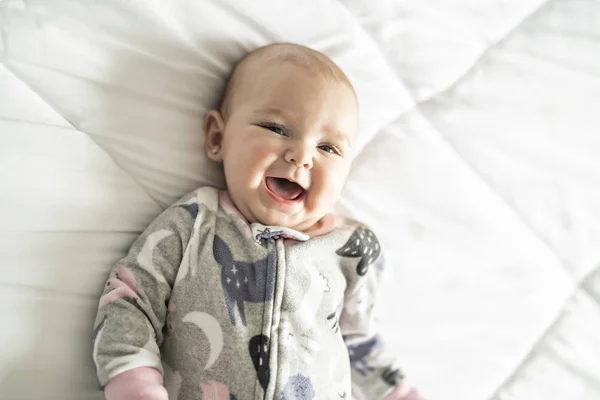 Una bambina carina su un letto bianco a casa — Foto Stock